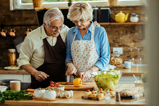 Happy senior couple making a healthy meal while cooking together in the kitchen.