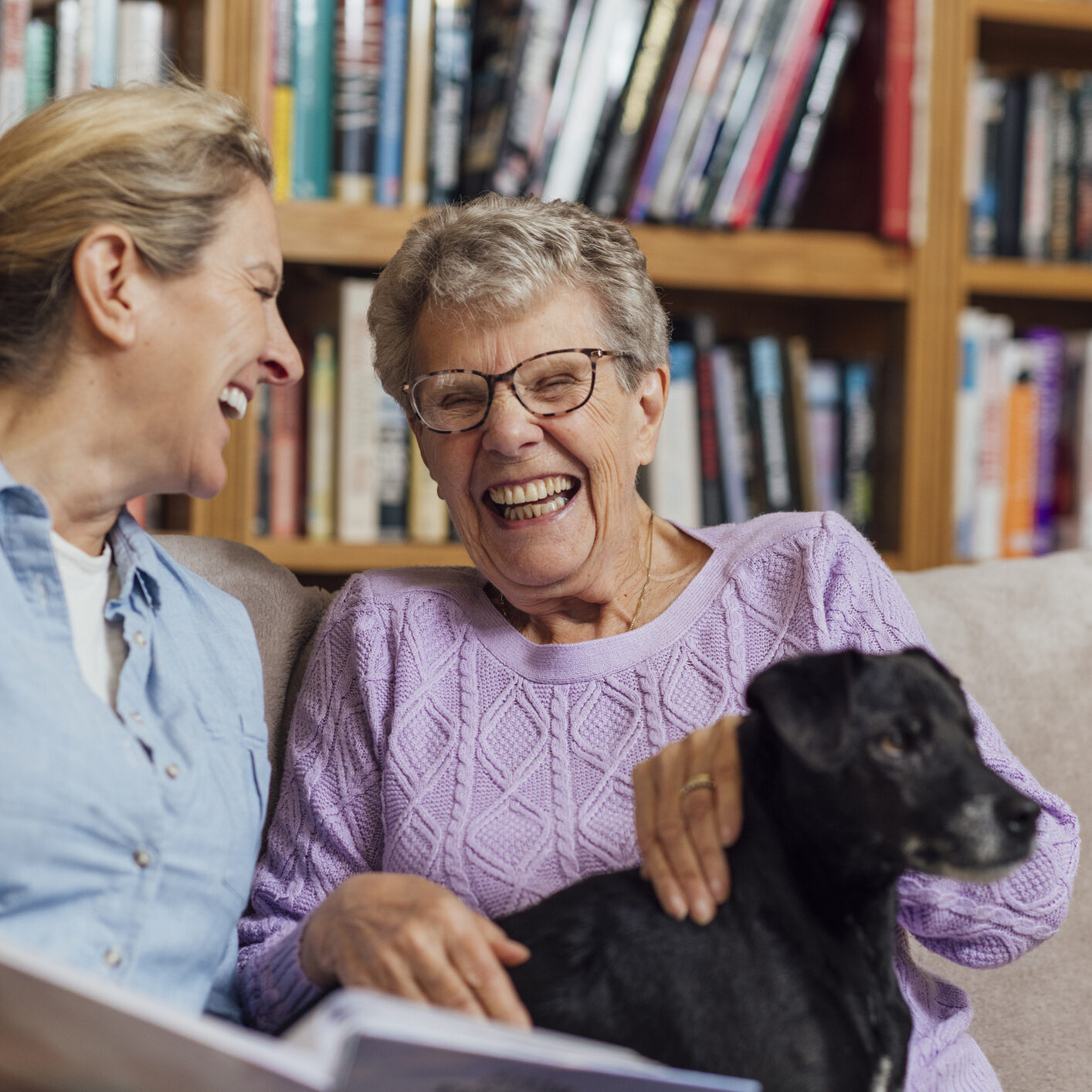 A mature woman sitting with her mother and pet dog on a sofa at home in Seghill, Northumberland. The senior woman is staying with her daughter for support and care as she has dementia and they are looking through a photo album together to aid her memory and strengthen their relationship.

Videos also available for similar scenario.